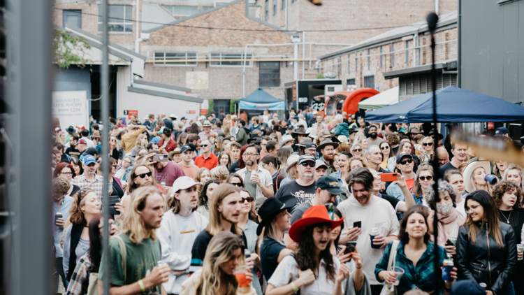 A group of people gather at a day festival in an urban carpark