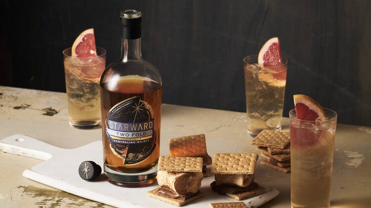 Bottles of starward whsikey and cocktails next to smores