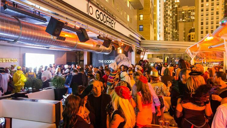A group of people gather in costume atop the I|O Godfrey rooftop bar