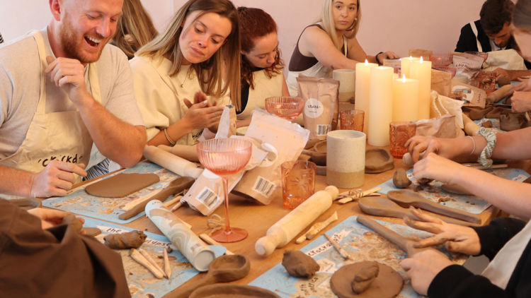 People laugh around a table while playing with clay 