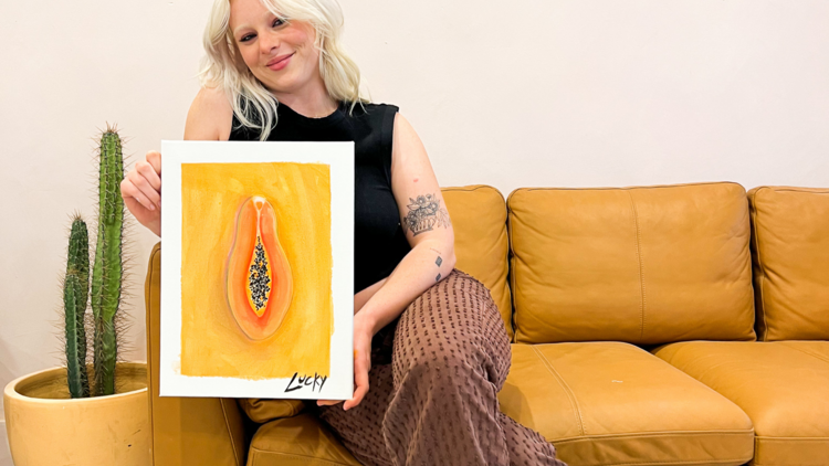 A girl holds up a bright picture of a papaya that she painted 