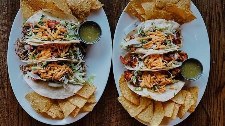 Two plates of tacos and tortilla chips.
