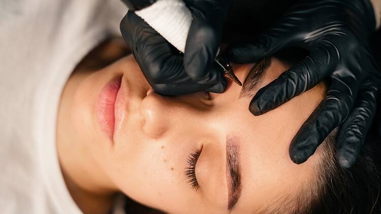 A woman receiving an eyebrow tattoo treatment.