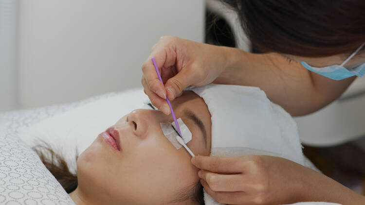A woman receiving an eyelash tinting treatment.