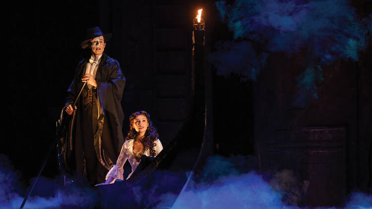 A scene from Phantom of the Opera musical where the Phantom rows Christine in a boat surrounded by mist.