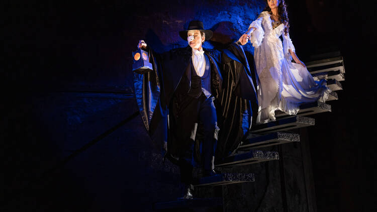 A scene from Phantom of the Opera musical where the Phantom leads Christine down a dark staircase.