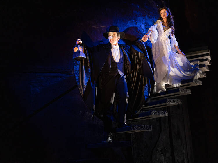 A scene from Phantom of the Opera musical where the Phantom leads Christine down a dark staircase.