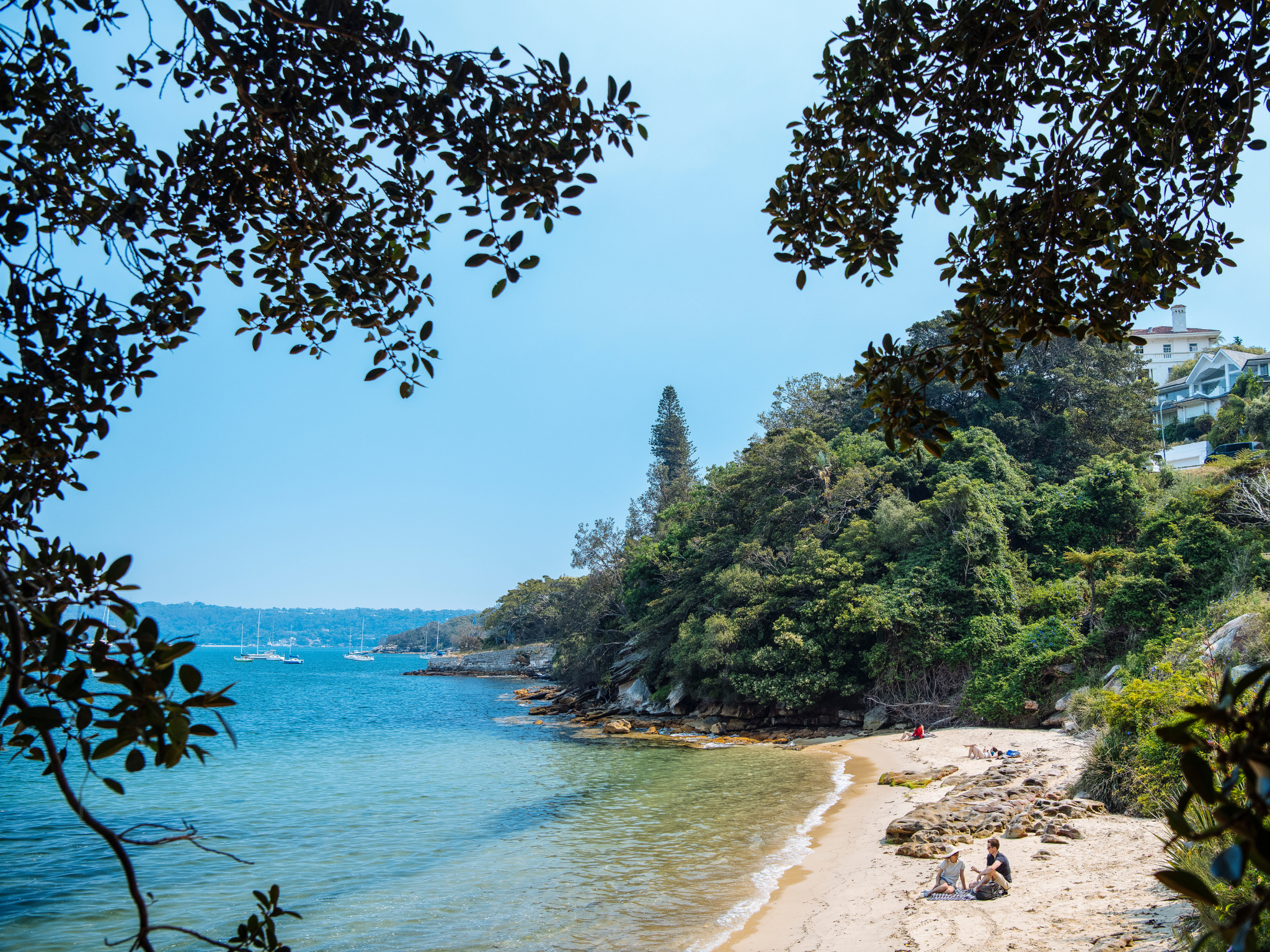 A landscape shot of the bright blue water and small white cove at Queens Beach