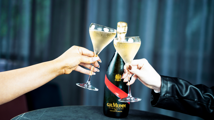 A pair of Champagne-filled glasses, cheersing.