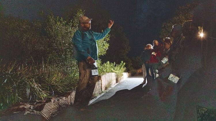 A First Nations guide leading a ghost tour at night