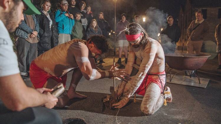 First Nations men light a fire with sticks