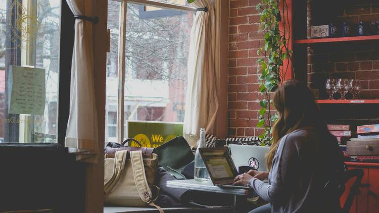 A woman is typing on a computer at a café