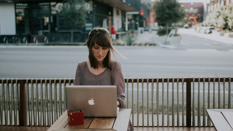 A woman is typing on a computer at a café