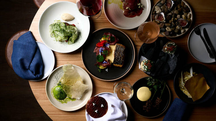 On a wooden table from a birds eye view there are many different Turkish dishes and glasses of wine