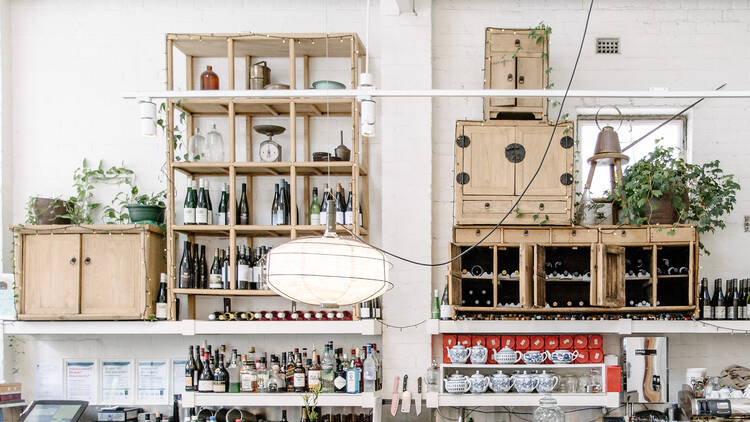 Behind the bar at David's there are crates filled with wine, hanging lanterns, teapots and other bottles in front of a white brick wall