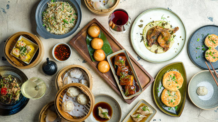 A birds eye view of a table filled with yum cha dishes including dumplings, pancakes, fried rice, duck and buns