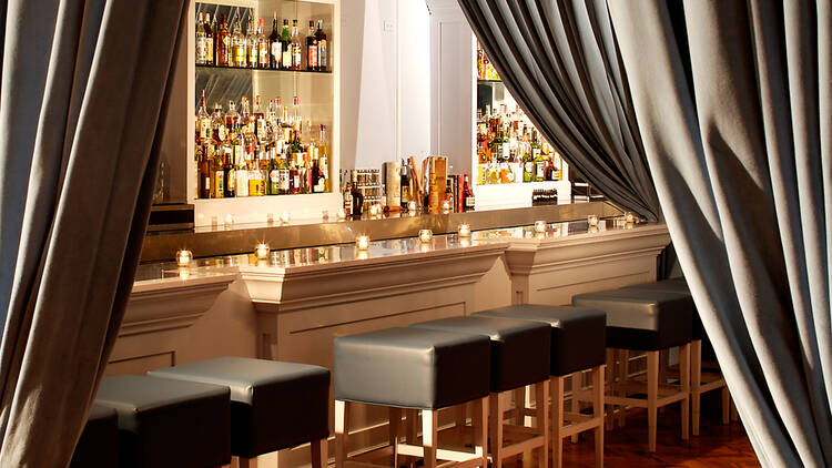 A grey curtain pulled back to reveal the bar at The Violet Hour