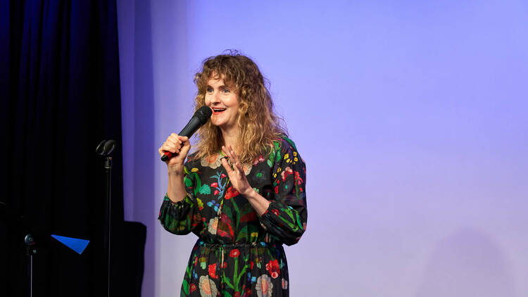 A performer stands on the stage holding a microphone.