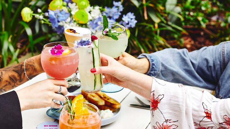Hands clinking colourful cocktails together