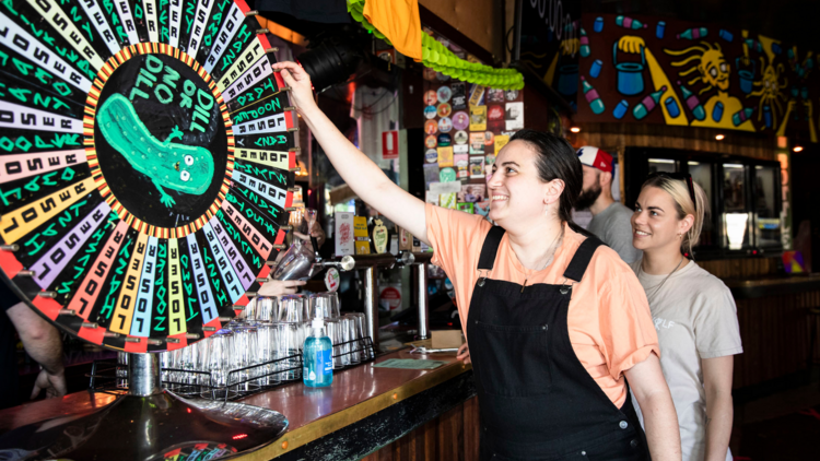 A woman spins a roulette wheel with a giant pickle in the middle