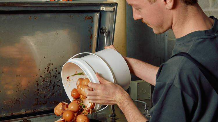 A person dumpling egg shells into a receptacle.