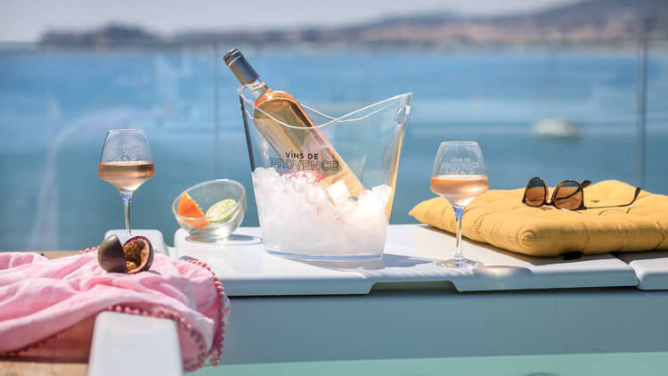 A bottle of rosé with two glasses by a spa overlooking the ocean