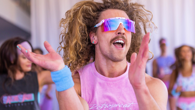 A guy with curly hair having just the best time doing aerobics