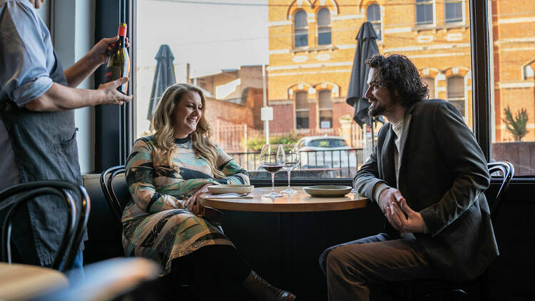 A couple dining at Mr Jones, and a sommelier showing them a bottle of wine.