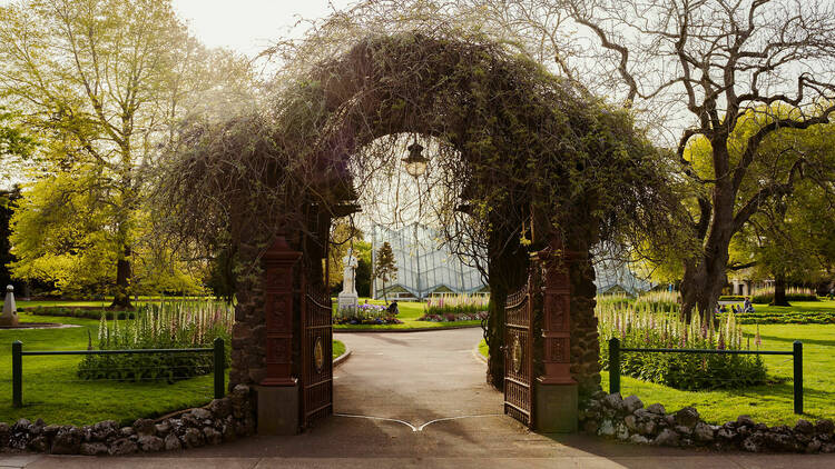 A plant-covered arch entryway to the Ballarat Botanical Gardens.