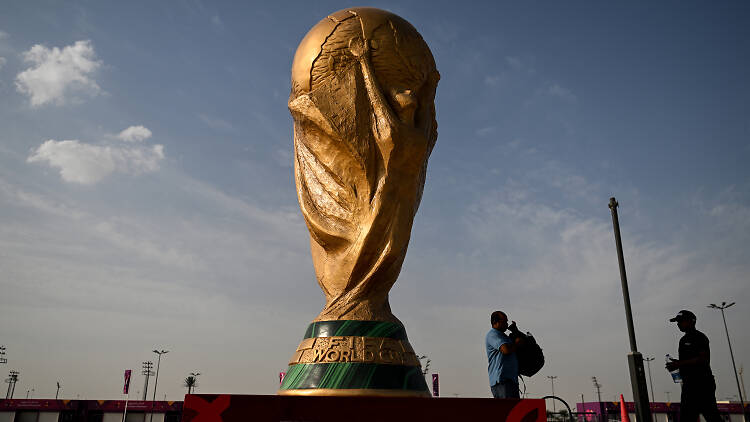 Men walk past a FIFA World Cup trophy replica outside the Ahmed bin Ali Stadium in Al-Rayyan on November 12, 2022, ahead of the Qatar 2022 FIFA World Cup football tournament. (Photo by Kirill KUDRYAVTSEV / AFP)