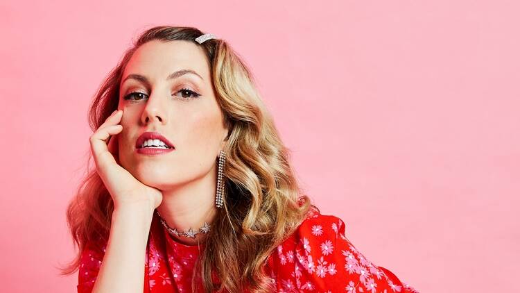 Hannah Reilly wearing a red and white dress in front of a pink background