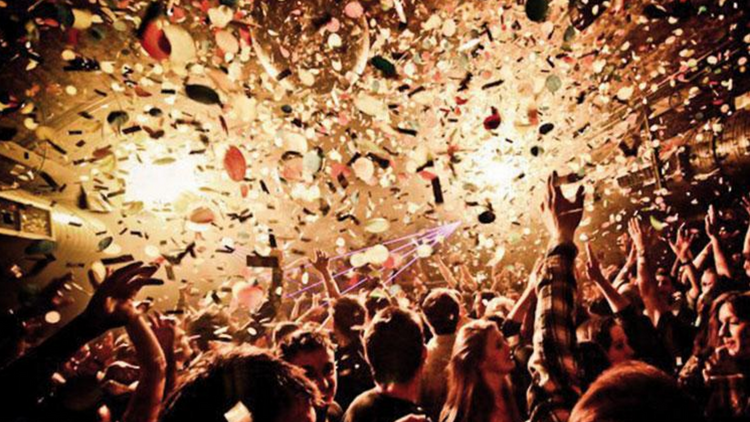 A group of people dancing beneath golden confetti