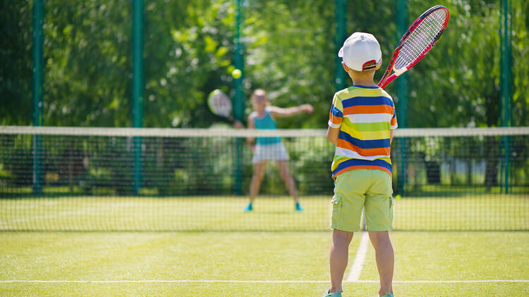 Little cute boy playing tennis on green court, Haynes Park Tennis Court