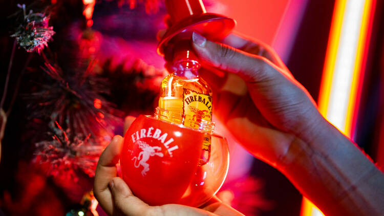 Two hands holding a Fireball Whisky Fire-bauble