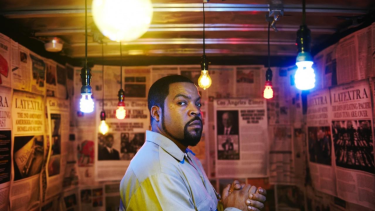 Hip-hop artist Ice Cube is pictured in a room with hanging light bulbs.