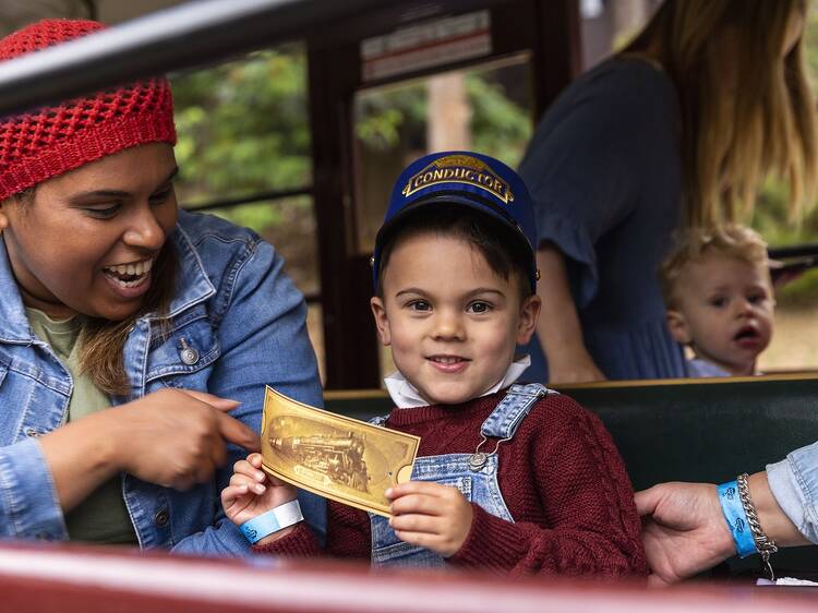 A small child holding a golden ticket aboard the Puffing Billy.