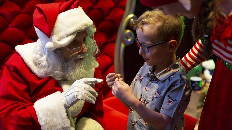 A small child interacting with Santa Claus.