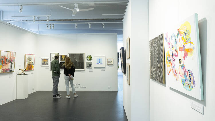A couple looking at artwork on walls in a gallery.