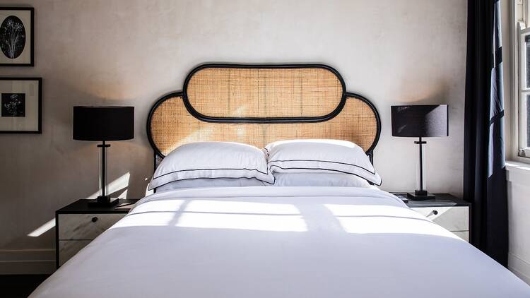 A photo of the bed in the Strand Hotel with a white doona and black lining