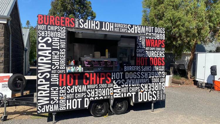A food truck dishing up chips, burgers and hot dogs.