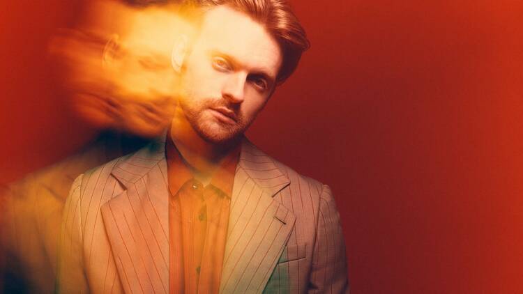 Musician and producer Finneas wearing a suit with his face blurred.