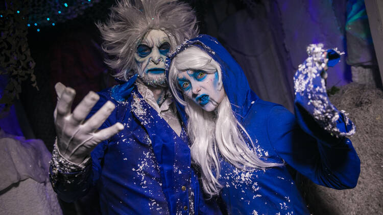 A man and woman in blue demon garb pose