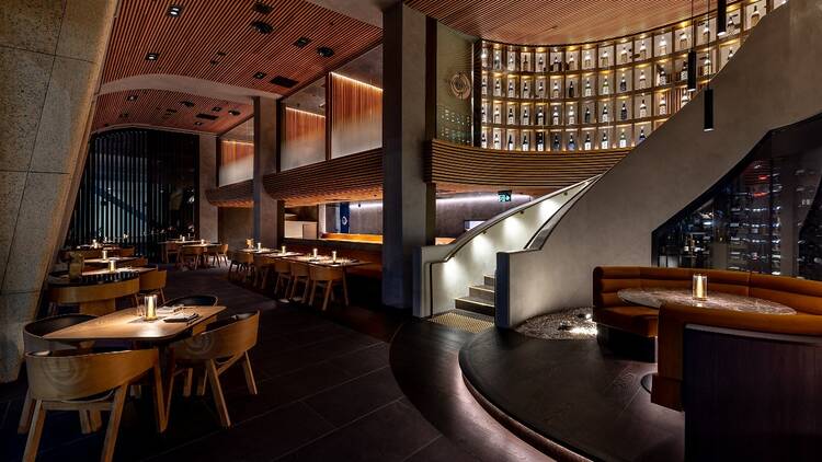 The inside of Oborozuki with a curved staircase, high ceilings and wooden tables 