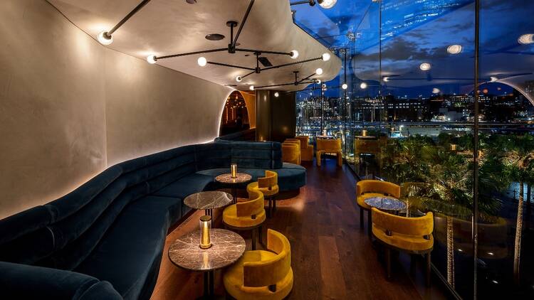 The inside of Oborozuki's bar with blue and yellow velvet seating and views of Circular Quay