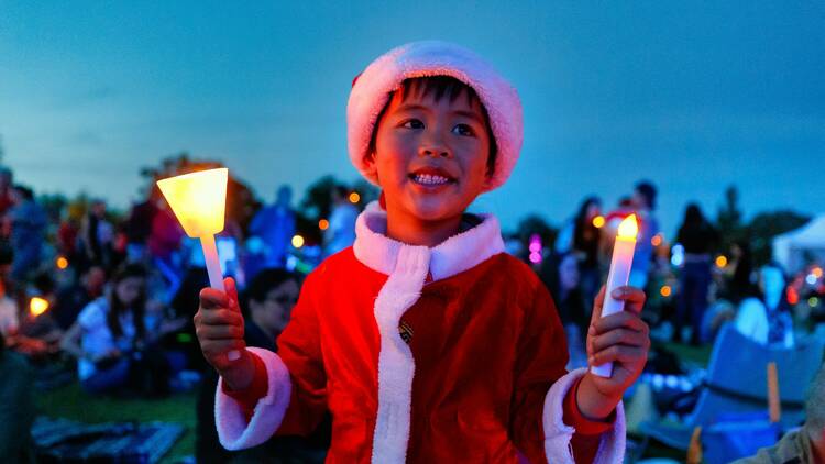 A young boy dressed up as Santa attends the Family Christmas at Central Park concert