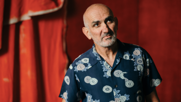 Paul Kelly in front of a red curtain