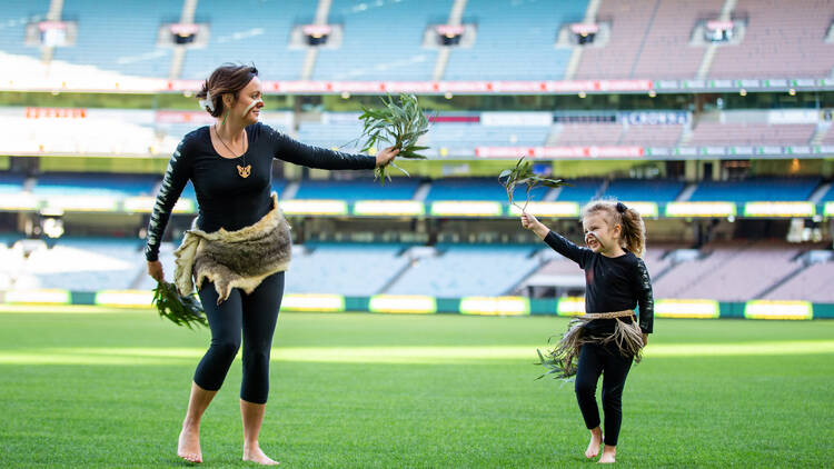 A woman and a child in the Djirri Djirri dance group, performing at a stadium.