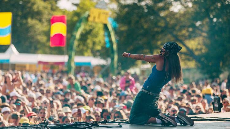 Musician G Flip performs on their knees in front of a large crowd.