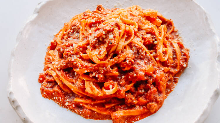 Inside 400 Gradi there is a white plate on a white table piled high with tomato based pasta