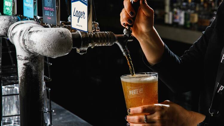 Someone pours a beer from a tap into a large glass